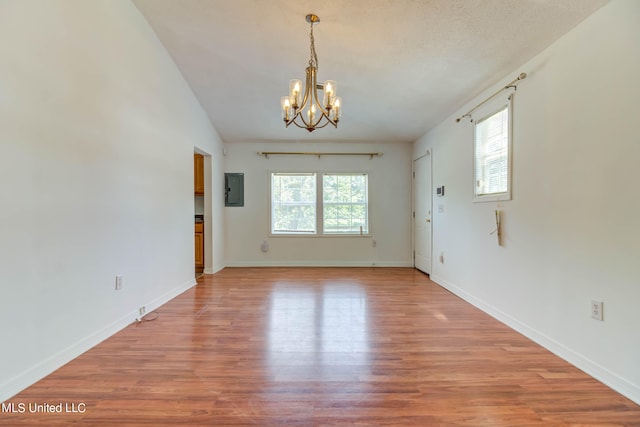 spare room featuring a healthy amount of sunlight, electric panel, vaulted ceiling, and hardwood / wood-style floors