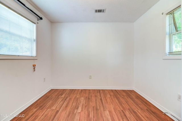 spare room with plenty of natural light and hardwood / wood-style floors