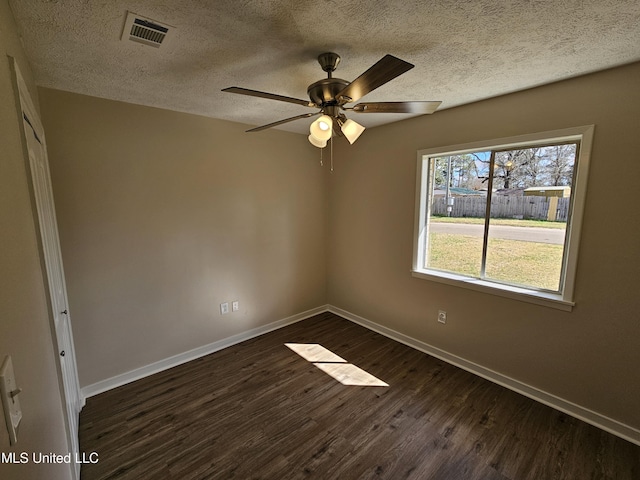 unfurnished room with visible vents, baseboards, dark wood-type flooring, and a textured ceiling