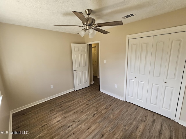 unfurnished bedroom featuring baseboards, visible vents, dark wood finished floors, a closet, and a textured ceiling