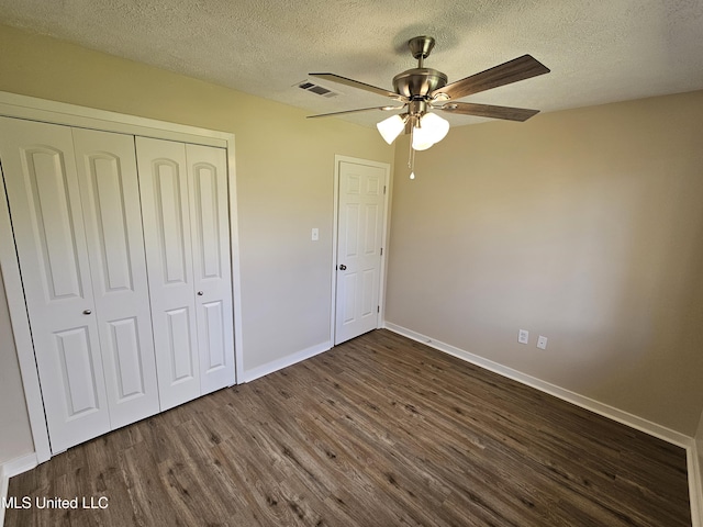 unfurnished bedroom featuring dark wood-style floors, visible vents, baseboards, a closet, and a textured ceiling