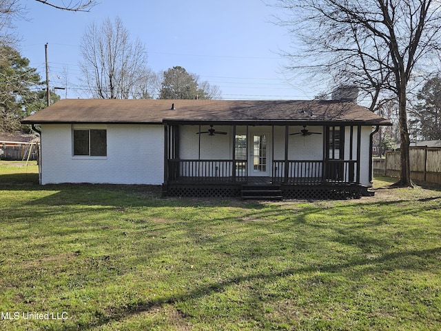 view of front facade with fence, a front yard, brick siding, ceiling fan, and a chimney