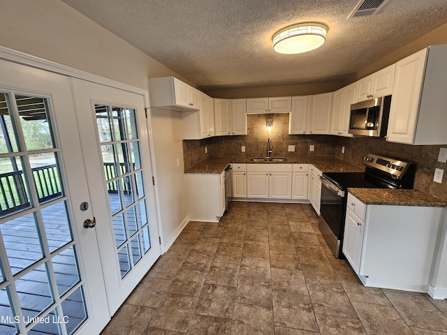 kitchen featuring visible vents, decorative backsplash, white cabinets, stainless steel appliances, and a sink