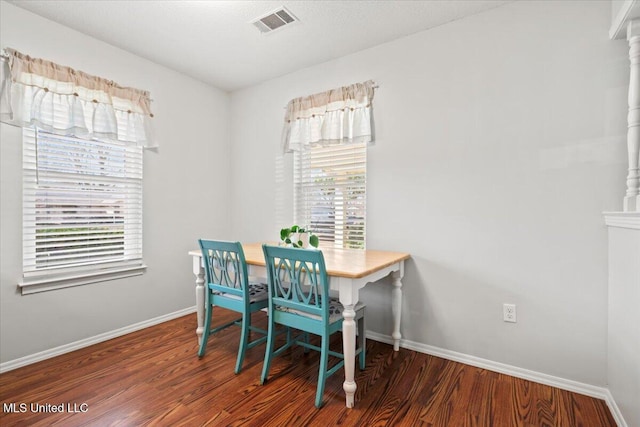 dining room featuring a wealth of natural light, visible vents, baseboards, and wood finished floors