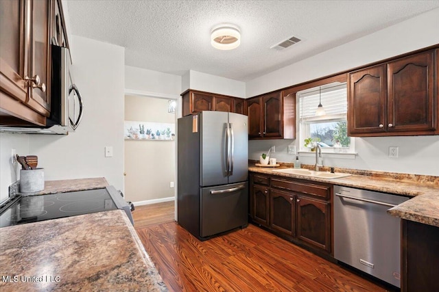 kitchen with visible vents, a sink, dark brown cabinetry, appliances with stainless steel finishes, and dark wood-style flooring