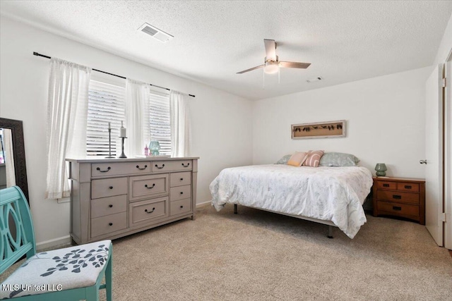 bedroom with visible vents, light colored carpet, ceiling fan, and a textured ceiling