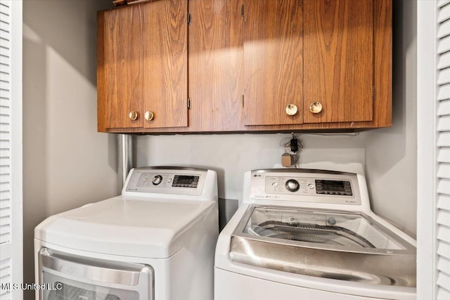 clothes washing area featuring washer and dryer and cabinet space