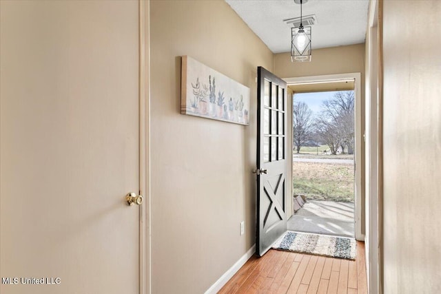 doorway to outside with wood finished floors, baseboards, and a textured ceiling