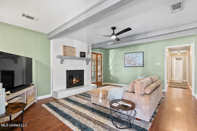 living room with visible vents, beam ceiling, wood finished floors, and a fireplace