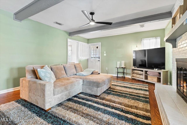 living room with beam ceiling, a brick fireplace, and wood finished floors