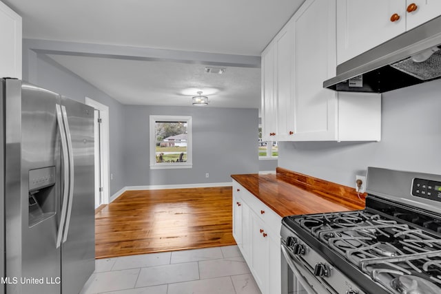 kitchen featuring visible vents, white cabinets, baseboards, range hood, and stainless steel appliances