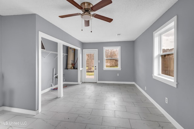 unfurnished room with a textured ceiling, ceiling fan, visible vents, baseboards, and marble finish floor