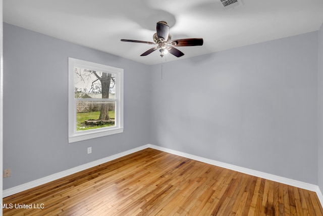 empty room with ceiling fan, light wood finished floors, and baseboards