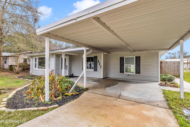 view of patio / terrace featuring an attached carport, concrete driveway, and fence