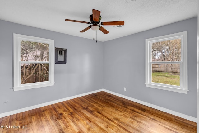 spare room with a ceiling fan, a textured ceiling, baseboards, and wood finished floors