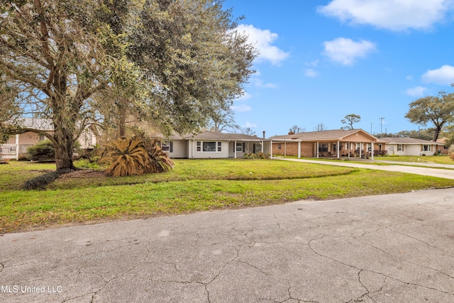 ranch-style house with driveway, brick siding, a front yard, and a residential view