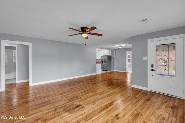 unfurnished living room with light wood finished floors, ceiling fan, visible vents, and baseboards