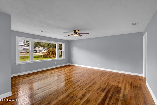 spare room with visible vents, baseboards, and wood finished floors