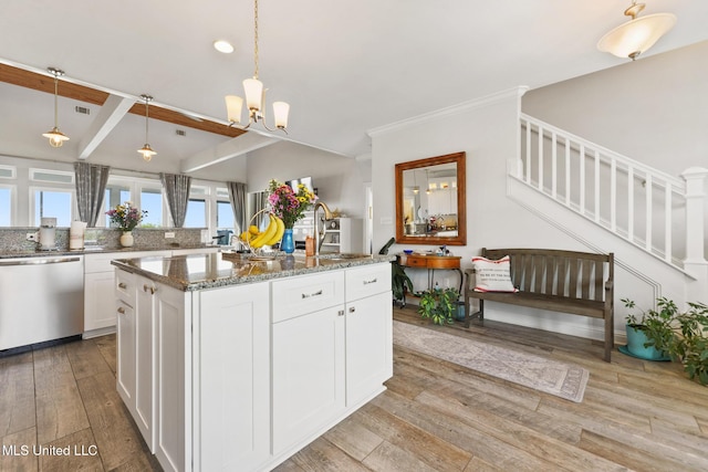 7101 Belle Fontaine Dr, Ocean Springs, MS 39564 - kitchen with stainless steel dishwasher, light wood-style floors, dark stone countertops, white cabinetry, and a kitchen island with sink