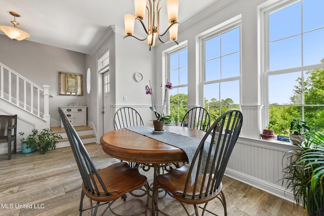 7101 Belle Fontaine Dr, Ocean Springs, MS 39564 - dining area with stairs, light wood-style flooring, a wainscoted wall, a chandelier, and ornamental molding