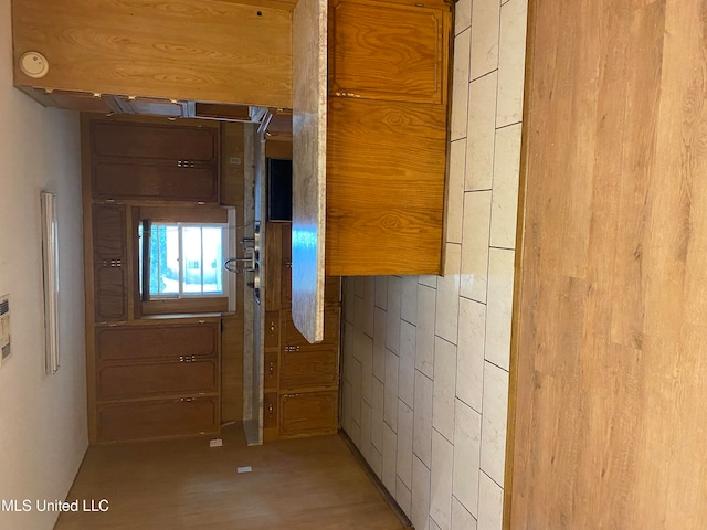 hallway featuring light hardwood / wood-style floors and wooden walls