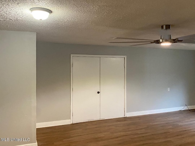 unfurnished bedroom featuring ceiling fan, a closet, dark wood-type flooring, and a textured ceiling