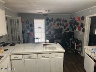 kitchen featuring white cabinetry, tile countertops, and crown molding