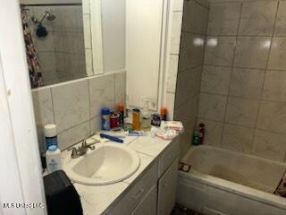 bathroom featuring vanity, tile walls, and tiled shower / bath