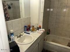 bathroom featuring tiled shower / bath combo, tile walls, and vanity