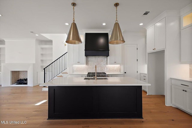 125 Water St, Madison, MS 39110 - kitchen with custom range hood, recessed lighting, white cabinetry, light countertops, and a center island with sink