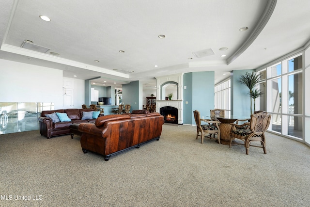 living room with a tray ceiling, crown molding, and light colored carpet