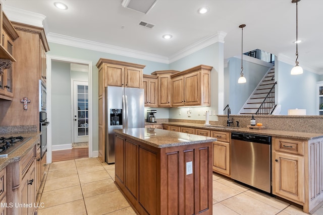 kitchen with stainless steel appliances, a kitchen island, a sink, visible vents, and crown molding