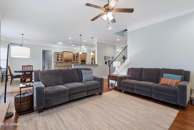 living room with recessed lighting, light wood-style floors, ornamental molding, ceiling fan, and stairs