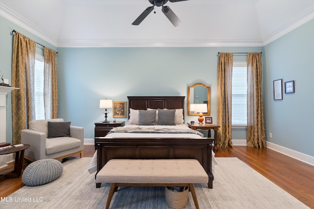 bedroom with multiple windows, a fireplace, baseboards, and wood finished floors