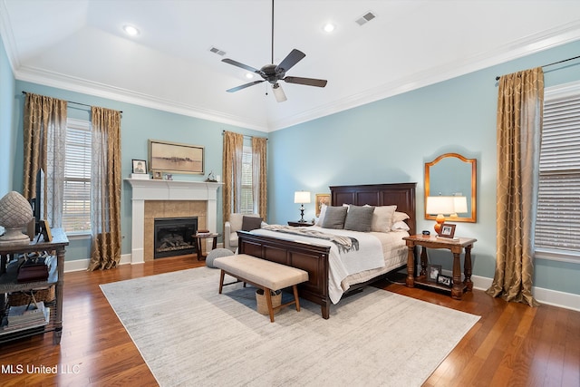 bedroom with a fireplace, visible vents, ornamental molding, baseboards, and hardwood / wood-style flooring