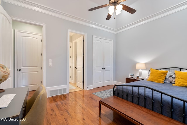 bedroom featuring baseboards, visible vents, crown molding, and wood finished floors