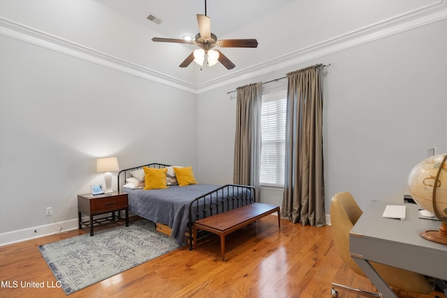 bedroom featuring light wood finished floors, baseboards, visible vents, ceiling fan, and crown molding