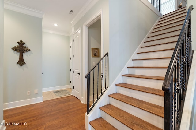 stairway with visible vents, baseboards, wood finished floors, crown molding, and recessed lighting