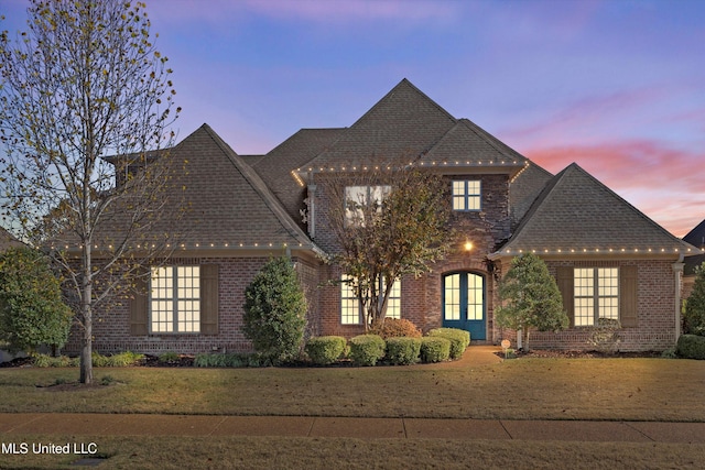 view of front of house with a shingled roof, french doors, and brick siding