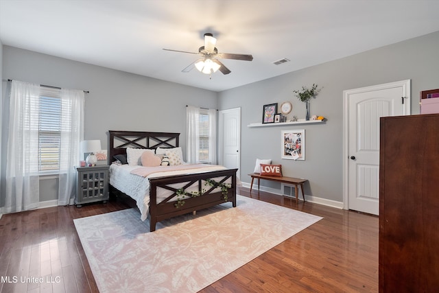 bedroom with a ceiling fan, wood finished floors, visible vents, and baseboards