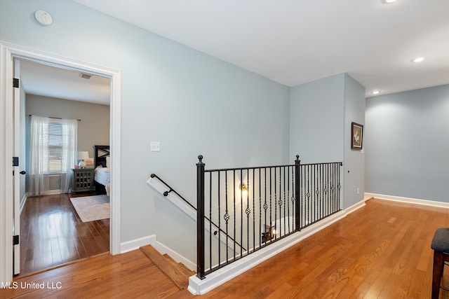 hall with recessed lighting, baseboards, an upstairs landing, and wood finished floors