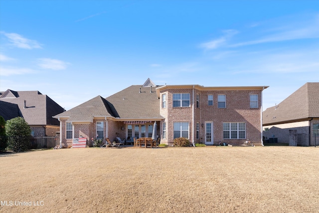 back of property featuring a yard, a patio, and brick siding