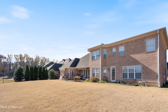 rear view of property with a patio area, brick siding, and a lawn