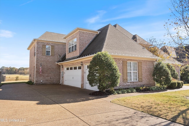 view of side of home featuring a shingled roof, brick siding, and driveway