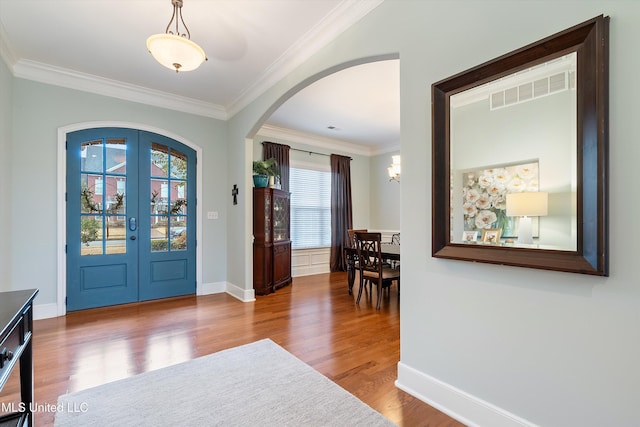 entryway featuring arched walkways, wood finished floors, visible vents, french doors, and crown molding