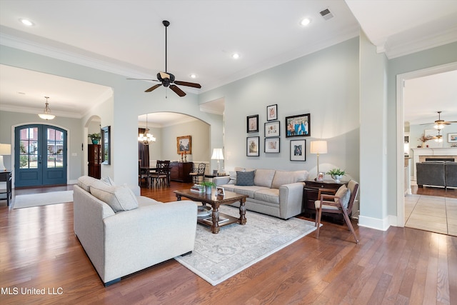 living area with arched walkways, french doors, visible vents, hardwood / wood-style floors, and baseboards