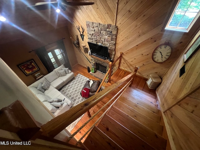 living room with ceiling fan, hardwood / wood-style flooring, and wood walls