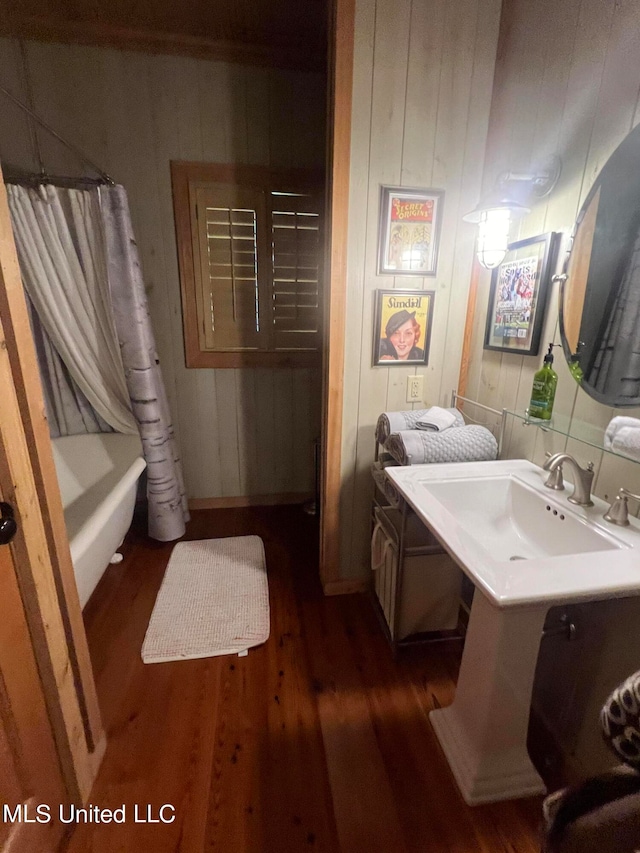 bathroom with shower / bath combination with curtain, hardwood / wood-style flooring, wooden walls, and vanity