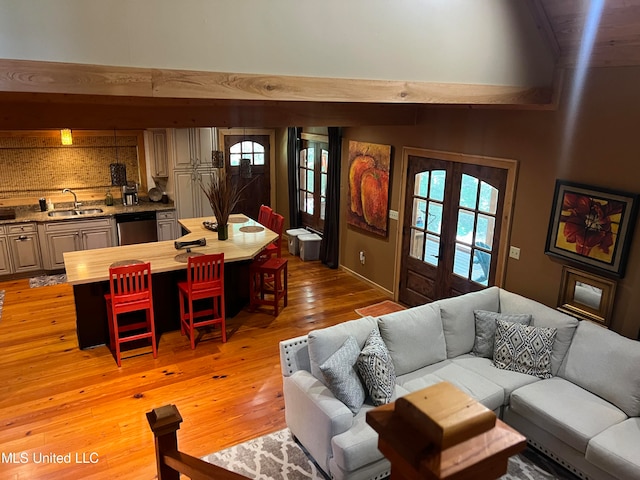 living room with a wealth of natural light, sink, french doors, and light hardwood / wood-style floors