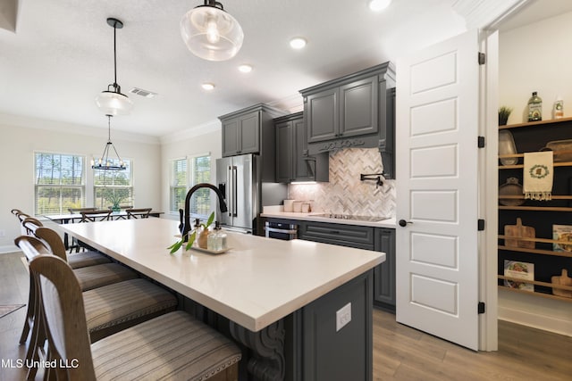 2918 Juliette Dr, Ocean Springs, MS 39564 - kitchen featuring crown molding, light wood-style floors, light countertops, a breakfast bar area, and decorative backsplash